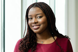 head shot of Augusta Business women dressed in formal dress Investment associate in the commercial litigation team Chantal Asante standing and posing for photo with a smile in bright modern London office room next to wide and floor to ceiling windows