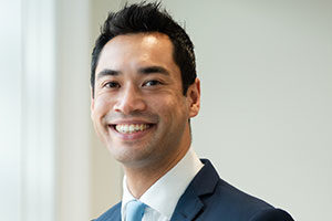 head shot of Investment manager and head of competition Law at Augusta Simon Latham standing and posing for photo in Augusta London offices while smiling and with hands in pocket