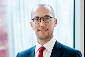 head shot of Augusta Business man dressed in suit Investment manager in Diligence and lawyer Chris Martin standing and posing for photo in bright modern London office room next to wide and floor to ceiling windows