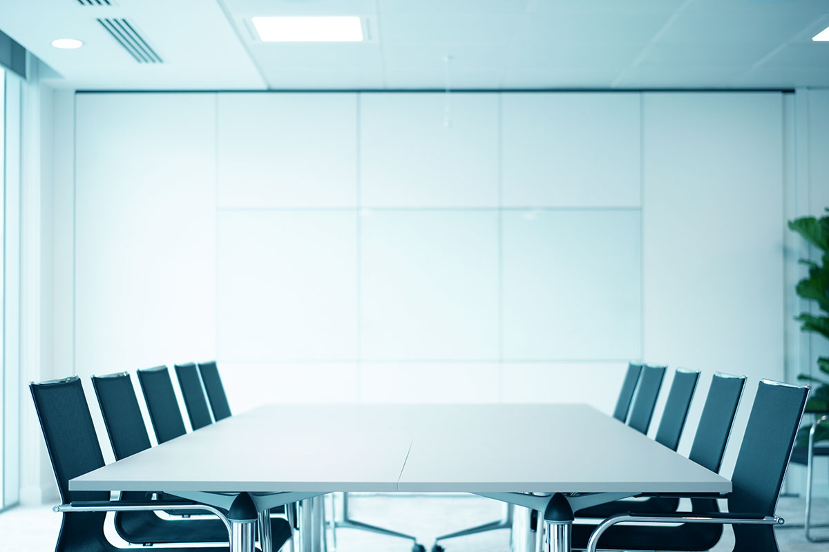 modern Augusta London office boardroom with long board table and chairs neatly arranged with bright wall and whiteboard in background