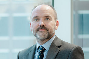 head shot of Augusta Business man dressed in suit Investment manager in Diligence and lawyer Glyn Rees standing and posing for photo in bright modern London office room next to wide and floor to ceiling windows