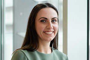 head shot of Augusta Business women dressed in formal clothes HR Manager Joanna Watts, smiling and posing for photo in bright modern London office room next to wide and floor to ceiling windows