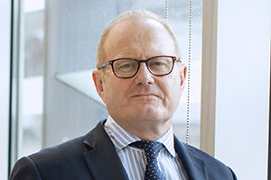 head shot of Managing Director and founding partner Louis Young standing and posing in business suit in Augusta London office with hands in his pockets