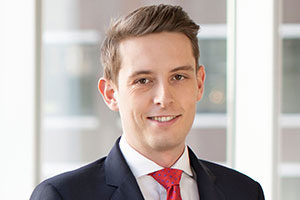 head shot of Augusta Business man dressed in suit investment manager in the structured projects team and Max Turner standing and posing for photo in bright modern London office room next to wide and floor to ceiling windows