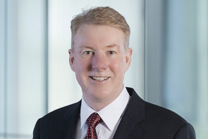 head shot of Augusta Business man dressed in suit managing director and founding partner Neill Brennan standing and posing for photo with a smile in bright modern Sydney Australia office room.