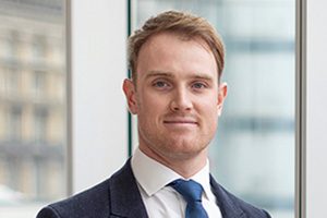 Head shot of Augusta Business man dressed in suit project manager Michael Taggart standing and posing for photo in bright modern London office room next to wide and floor to ceiling windows