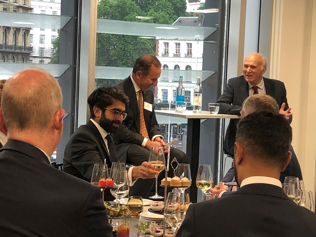 Liberal Democrats Leader Sir Vince Cable sitting and answering questions to Managing Director and Founding Partner Robert Hanna in Augusta London offices with Crowd group of people sitting at a round table with drinks and canapes listening to discussion