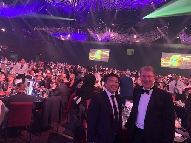 Managing Director Neill Brennan and Investment Manager Zac Low standing in front of large crowd of business people at awards event