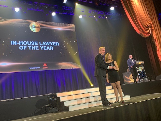 Managing director and founding partner Neill Brennan presenting award to winning law firm on stage at the Australian awards show