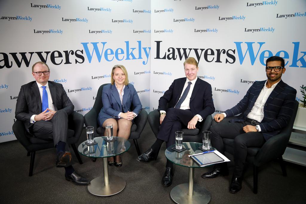 4 business people sitting side by side, facing direct to camera and posing for photo with press boards behind them title Lawyers weekly